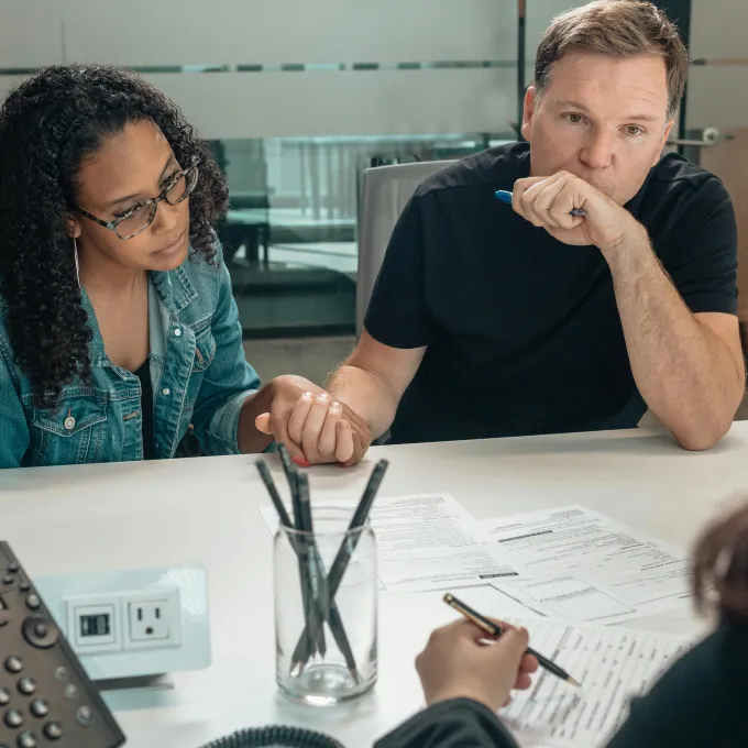 "a couple reviewing forms while talking to a government official"
