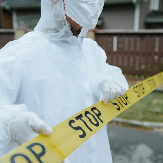 "a man in full protective gear standing behind a barrier of caution tape""